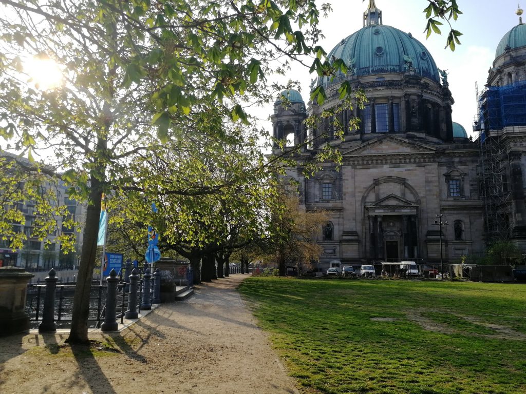 a path leading past some green trees to an ornamental church in a city